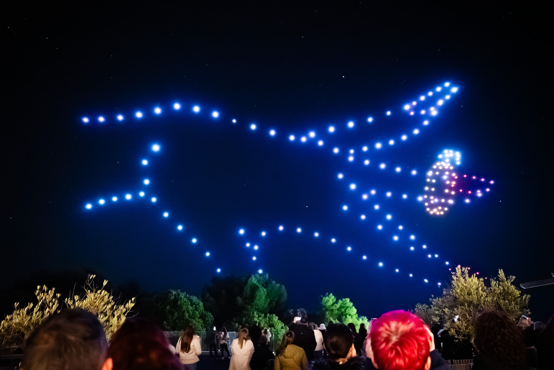 Drone ring formation glowing above a wedding crowd at night
