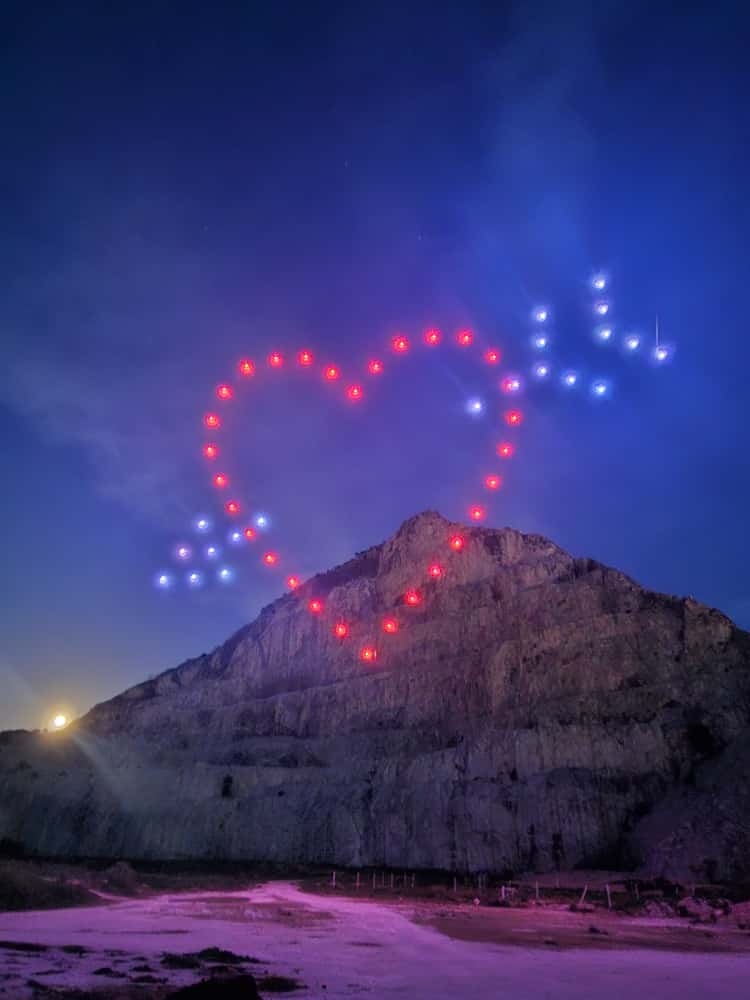 Heart-and-arrow drone formation above a mountain
