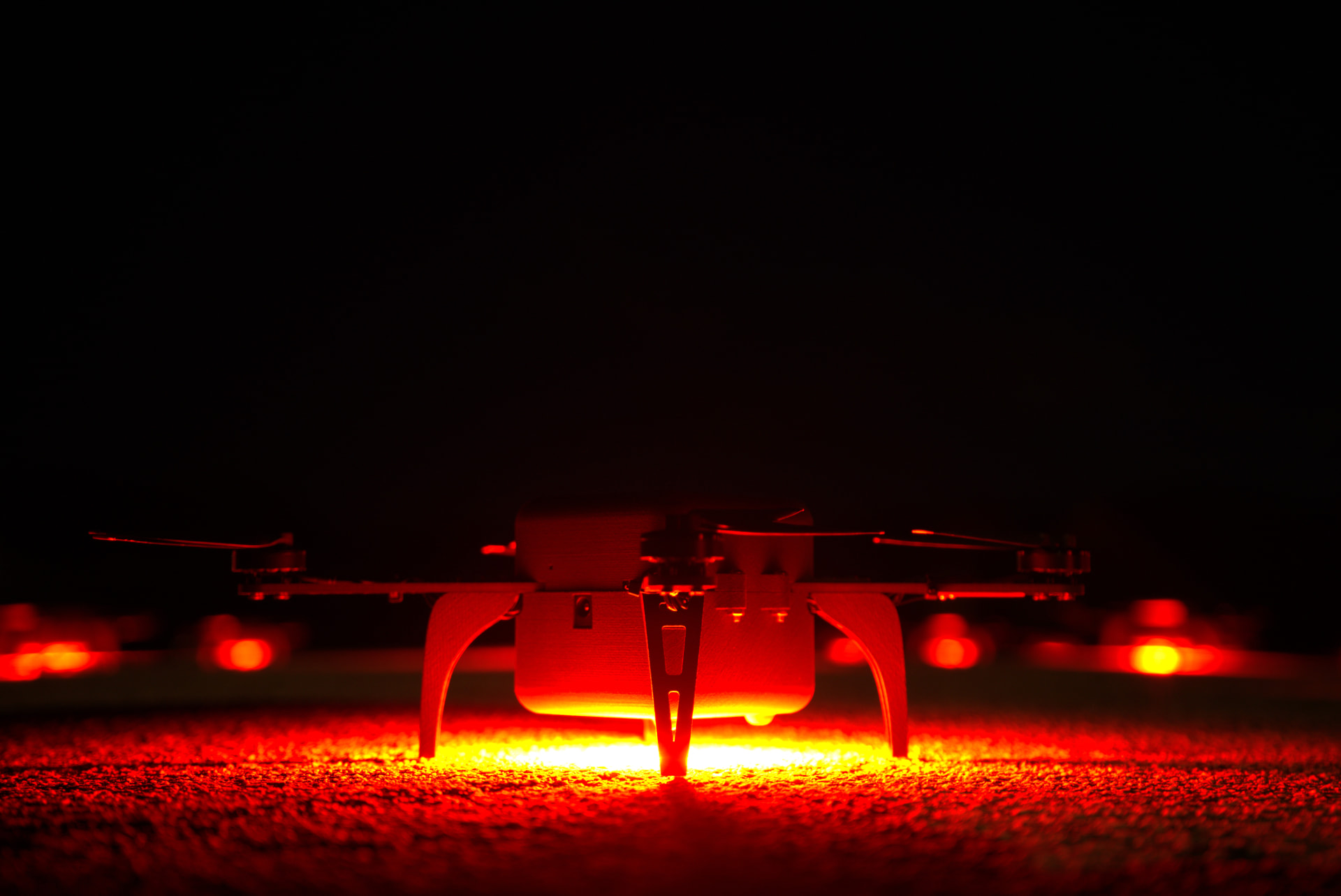 LightX drone with its LED payload glowing red during a night test