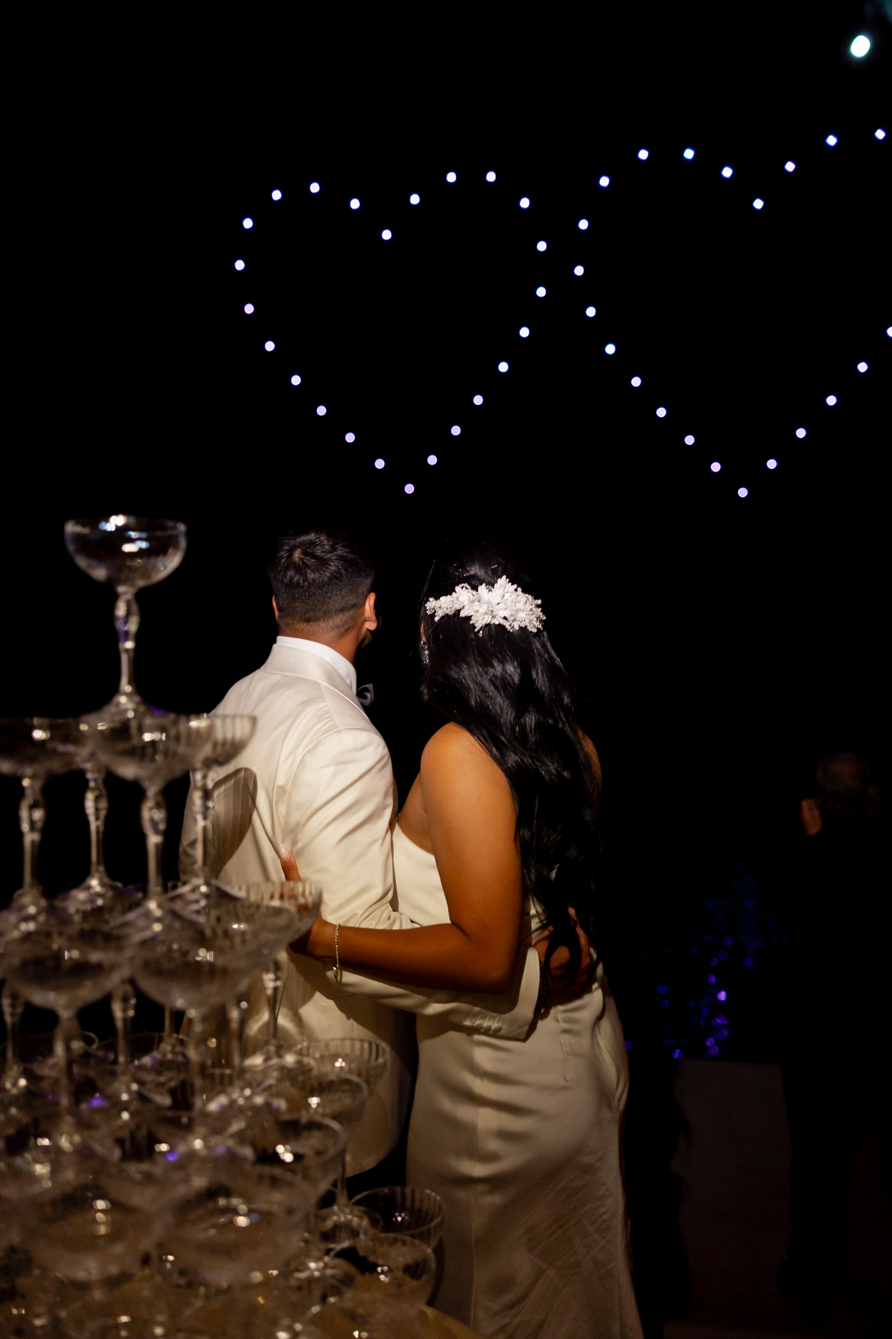 Two interlocking drone hearts glowing above a wedding reception