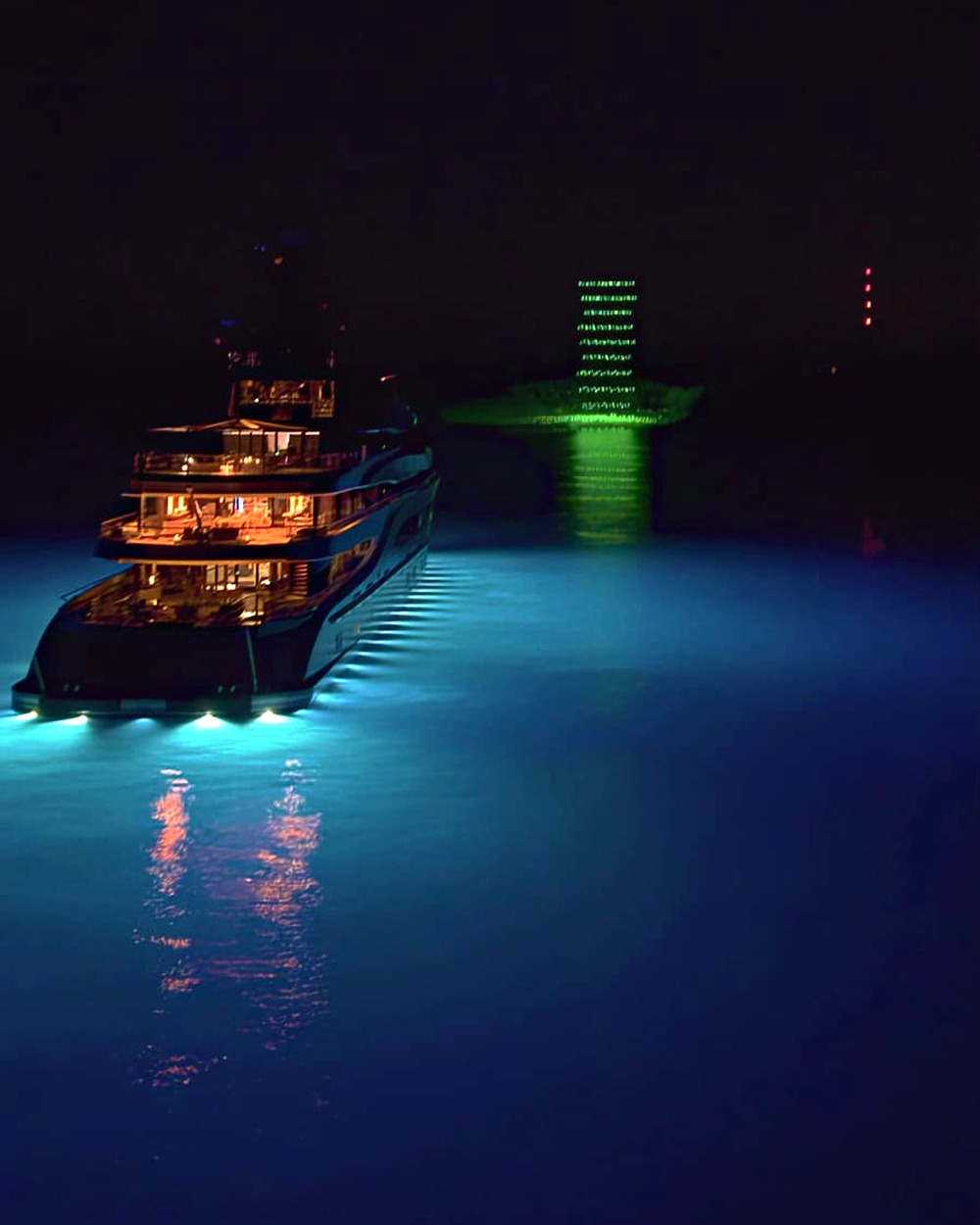 Green drone lighthouse figure above a luxury yacht
