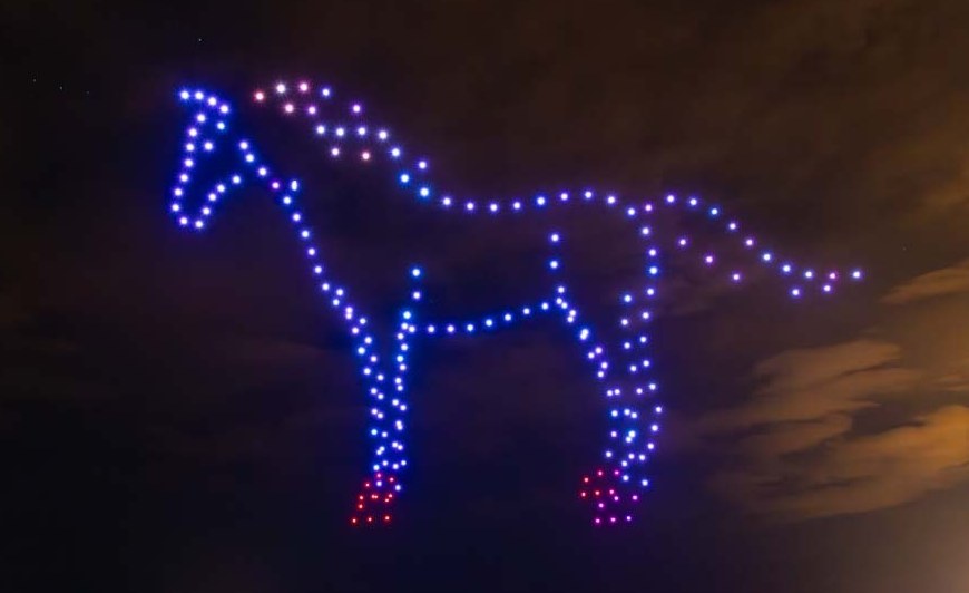 Drone horse formation glowing above the shoreline