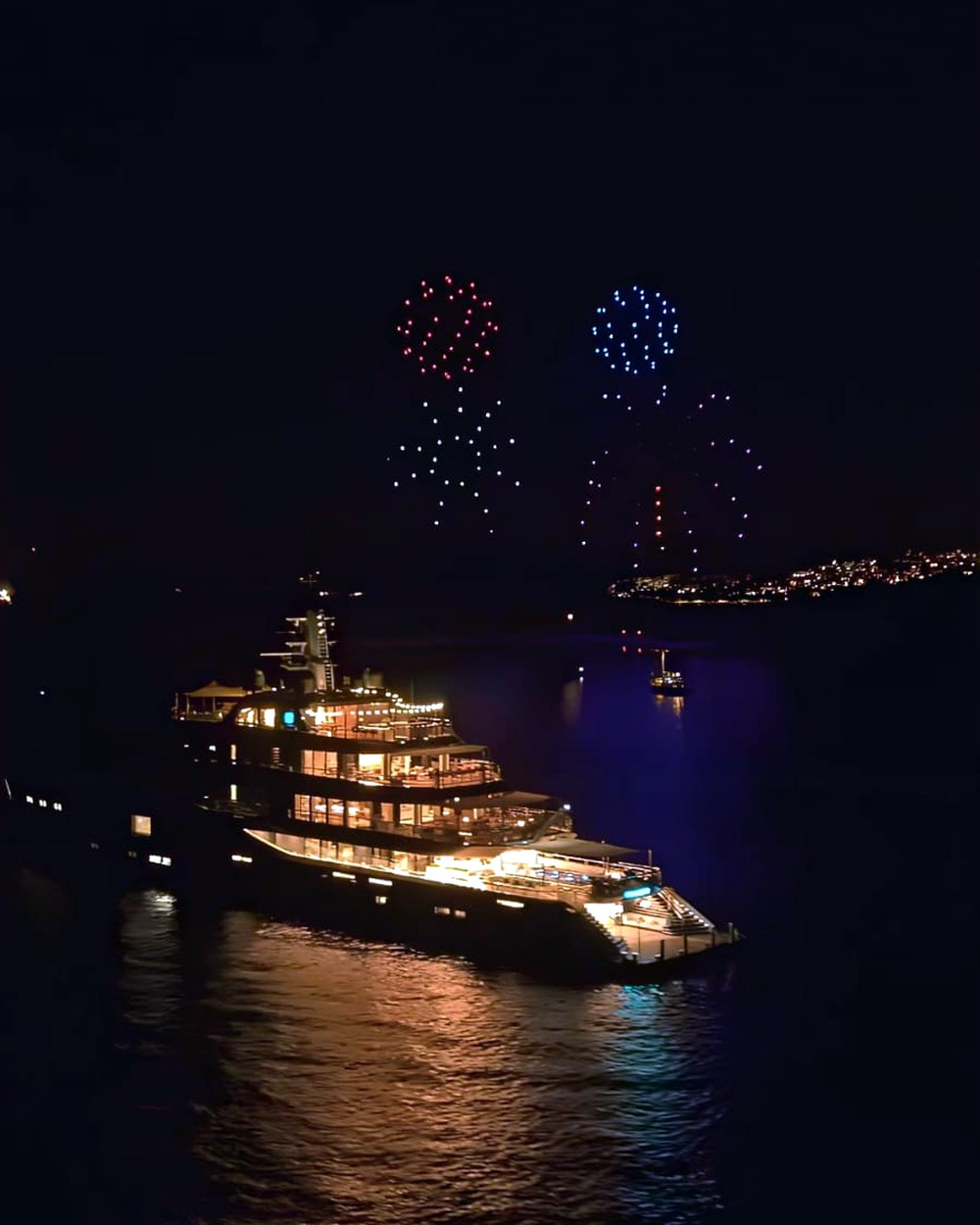 Red and blue drone bursts over a yacht on the water